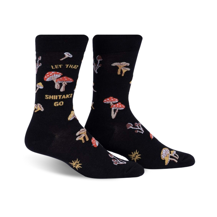Pair of black crew socks featuring a whimsical mushroom design and the phrase 'Let That Shiitake Go'.  Red and gold mushroom illustrations scattered across the socks.