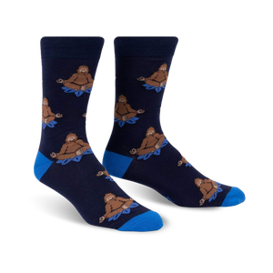 Pair of navy blue crew socks with a repeating pattern of brown Bigfoot figures meditating on blue lotus flowers.  Features a royal blue cuff.