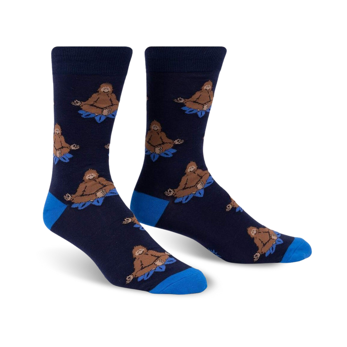 Pair of navy blue crew socks with a repeating pattern of brown Bigfoot figures meditating on blue lotus flowers.  Features a royal blue cuff.