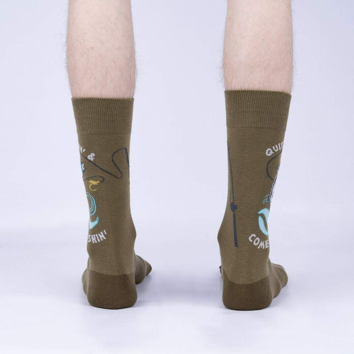 A pair of olive green socks with a pattern of blue and white fish and fishing hooks. The left sock says 