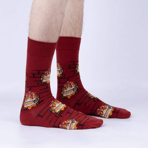 A pair of red crew socks with a pattern of cartoonish fireplaces with flames and logs.