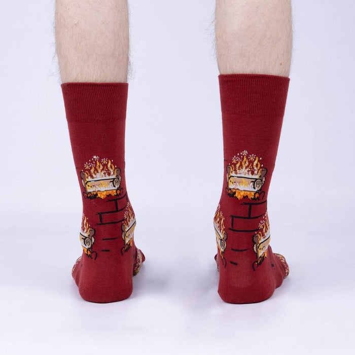 A pair of red crew socks with a pattern of cartoonish fireplaces with flames and logs.