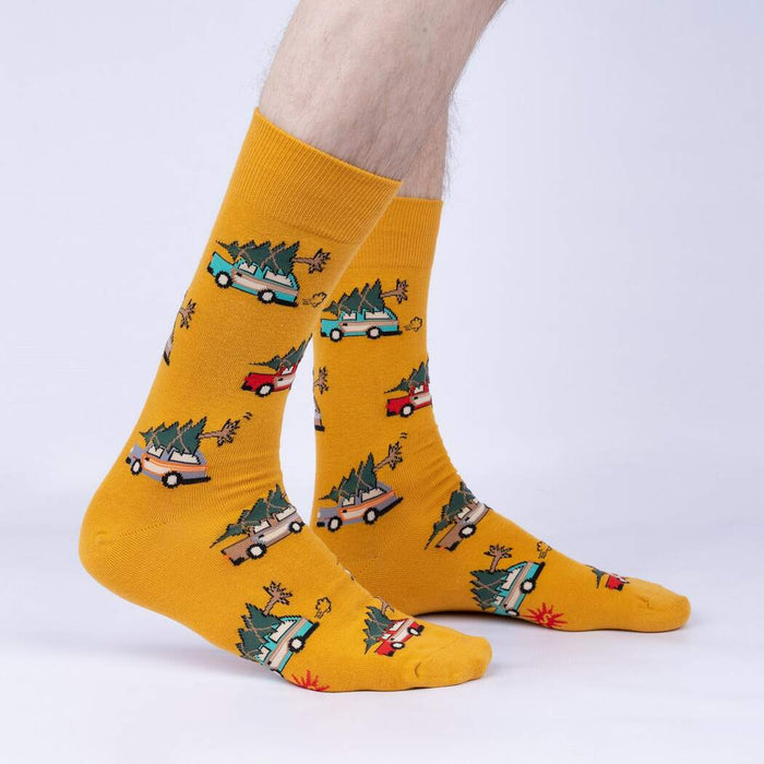 A pair of yellow socks with a pattern of cartoon cars with Christmas trees on their roofs.