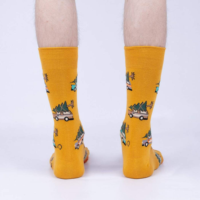 A pair of yellow socks with a pattern of cartoon cars with Christmas trees on their roofs.