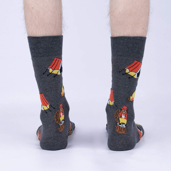 A pair of gray socks with a pattern of cartoon beavers camping on them. The beavers are wearing red hats and holding camping gear.