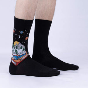 A pair of black socks with a design of a rocket ship on each sock. The rocket ship is surrounded by planets and stars.