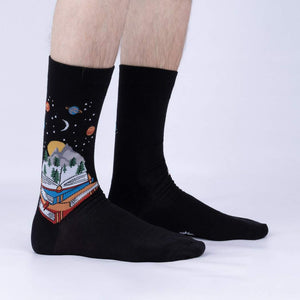 Lifestyle shot of a person's legs wearing the black 'Take a Look It's in a Book' socks, showcasing the design and fit.