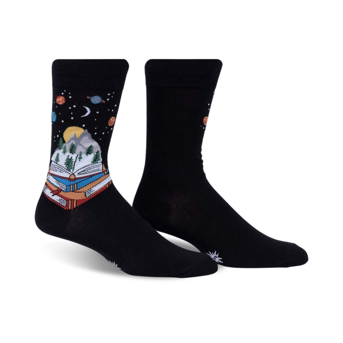Pair of black crew socks featuring a whimsical design of a book with a mountain landscape inside, set against a starry night sky with planets.
