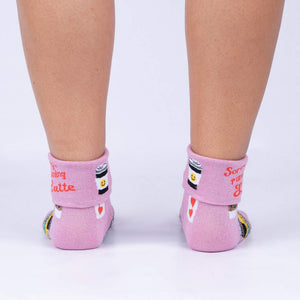 A pair of pink socks with a pattern of coffee cups, books, and the words 