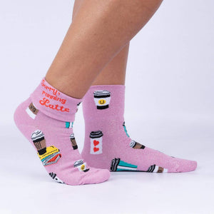 A pair of pink socks with a pattern of coffee cups, books, and the words 