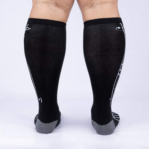 A pair of black knee-high socks with a white giraffe pattern on the back.