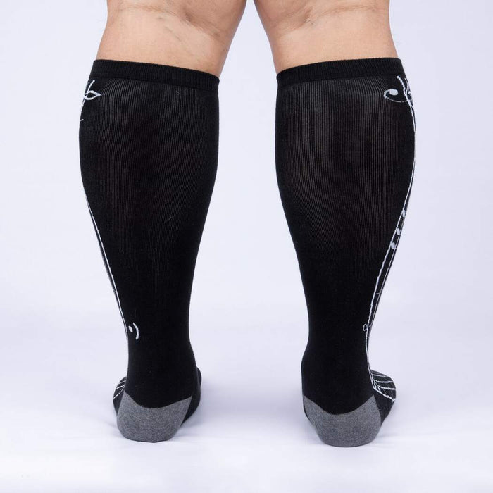 A pair of black knee-high socks with a white giraffe pattern on the back.