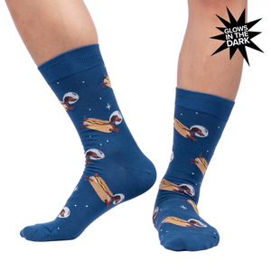 Lifestyle shot of a person wearing the 'Weiner Dogs, In Space!' socks, showcasing the glow-in-the-dark effect.