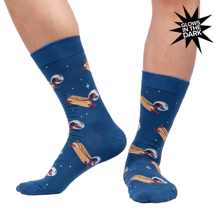 Lifestyle shot of a person wearing the 'Weiner Dogs, In Space!' socks, showcasing the glow-in-the-dark effect.