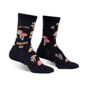 Pair of black crew socks with a whimsical mushroom and 'Let That Shiitake Go' design. Red and gold mushrooms are scattered across the black fabric.