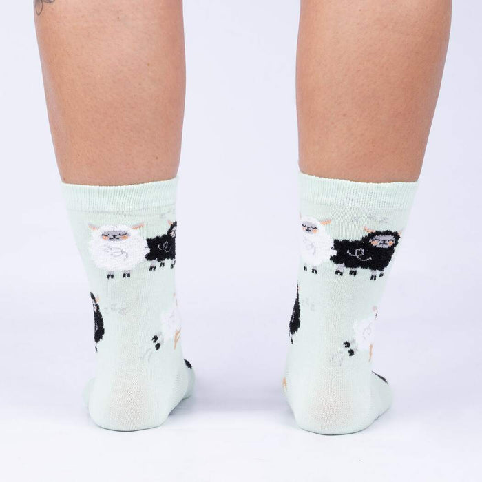 A pair of light green socks with a pattern of black and white sheep.