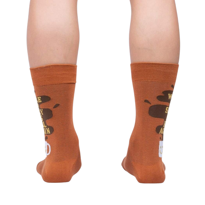 Rear view of the socks on a person's legs, highlighting the back design of the coffee cup and text.