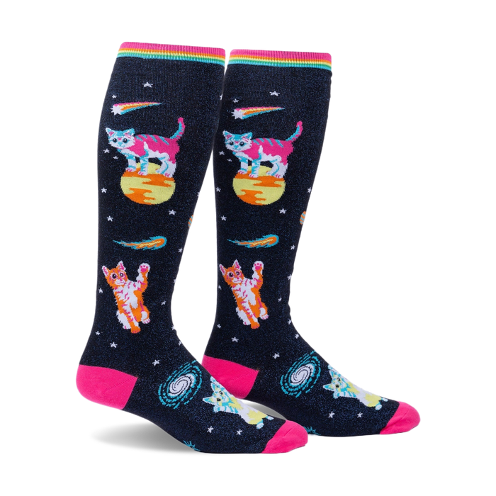 Pair of knee-high socks on a white background. Black background with pink, orange, and teal space cats, stars, and comets. Rainbow top cuff.