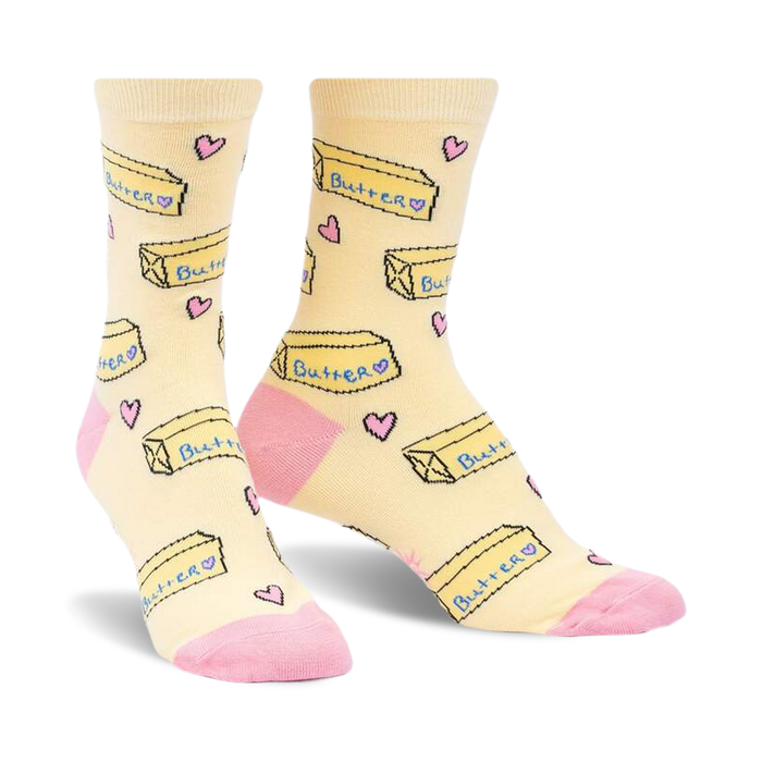 Pair of pastel yellow crew socks with a repeating pattern of butter pats and pink hearts. Pink accents on the heel and toe.