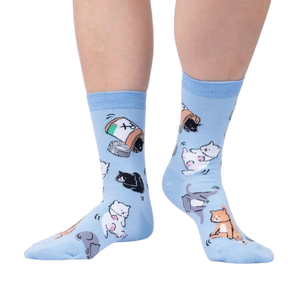 Lifestyle shot of a person wearing the light blue crew socks with cat and pill bottle design.