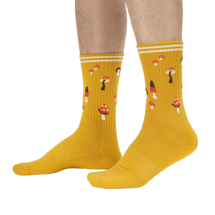 A pair of yellow socks with a pattern of red and white mushrooms.