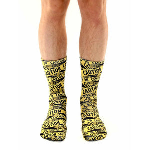 Lifestyle shot of a person's legs wearing the 'Caution' socks. The socks are the main focus, against a white background.