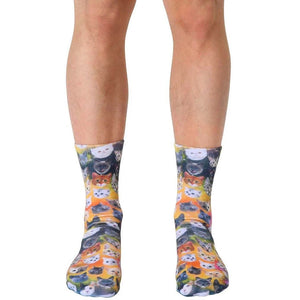 Crew socks showcasing a vibrant galaxy of adorable cat faces in various colors on a yellow-orange background.