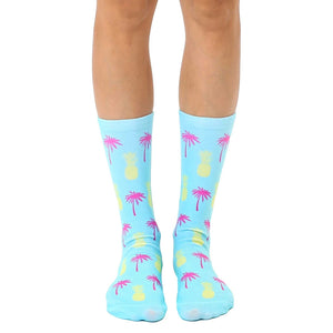 Pair of light blue crew socks with a fun, repeating pattern of pink palm trees and yellow pineapples.