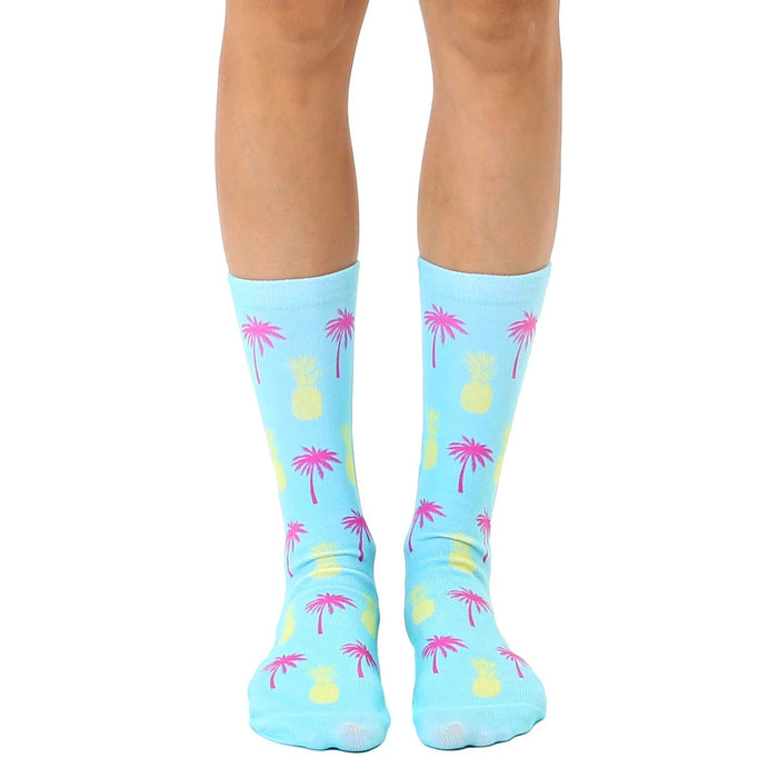 Pair of light blue crew socks with a fun, repeating pattern of pink palm trees and yellow pineapples.