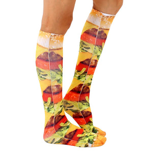 A pair of legs is shown wearing a pair of knee-high socks that have a photo-realistic image of a cheeseburger printed on them.
