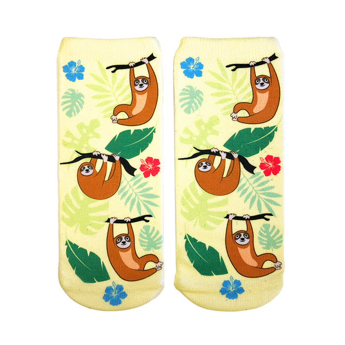 Pair of pastel yellow ankle socks featuring illustrated brown tree sloths hanging from branches, surrounded by tropical leaves and hibiscus flowers. }}