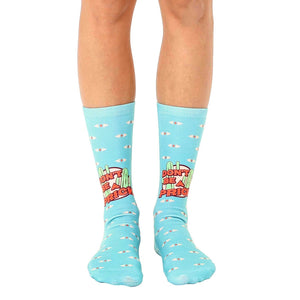 A pair of light blue crew socks with a 'Don't Be A Prick' slogan, cacti, and small eye illustrations.