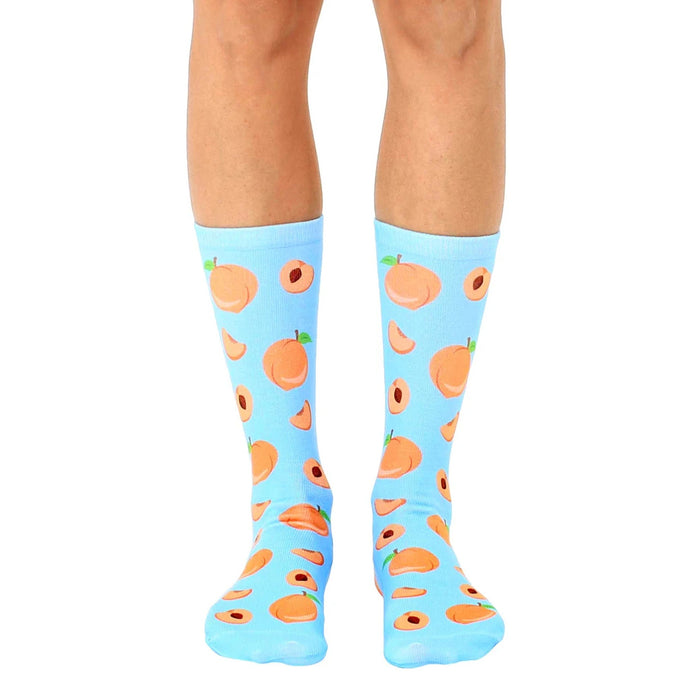 Pair of light blue crew socks with an all-over print of peaches and peach slices.