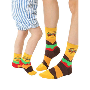 Adult and child crew socks in yellow, brown, and green.  Burger graphics and stripes decorate these fun, matching food socks.