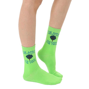 A pair of women's lime green crew socks with the phrase 'The apple doesn't fall far from the tree' and a small tree graphic.
