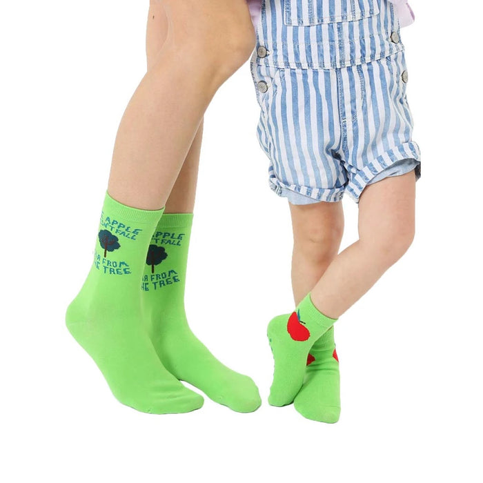 Adult and child lime green crew socks. Adult socks feature 'The apple doesn't fall far from the tree' text and a small tree graphic. Child socks have a red apple graphic.