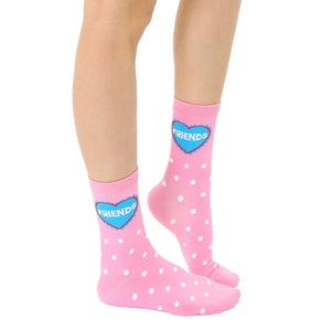 Close-up of adult-sized pink polka dot socks with a blue heart that says 'Friends'.