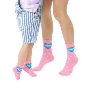 Adult and child pink crew socks with white polka dots and a blue heart that says 'Best Friends'.