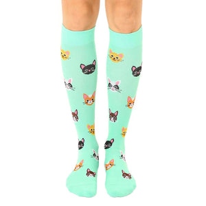 Pair of mint green knee-high socks with a pattern of cute, colorful cat faces.
