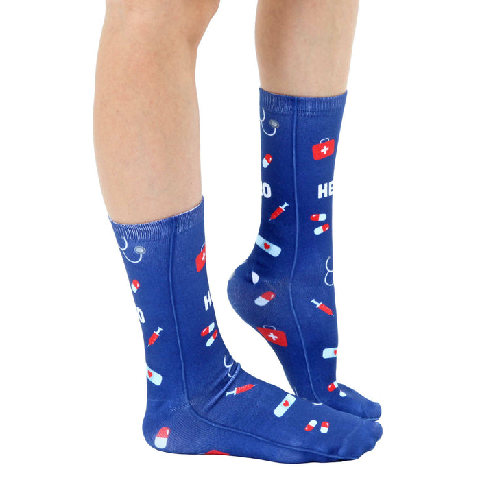 A pair of blue socks with a pattern of red and white pills, syringes, and caduceus symbols. The word 