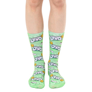 A pair of light green crew socks with a whimsical design featuring cartoonish dollar bills and toilet paper rolls.