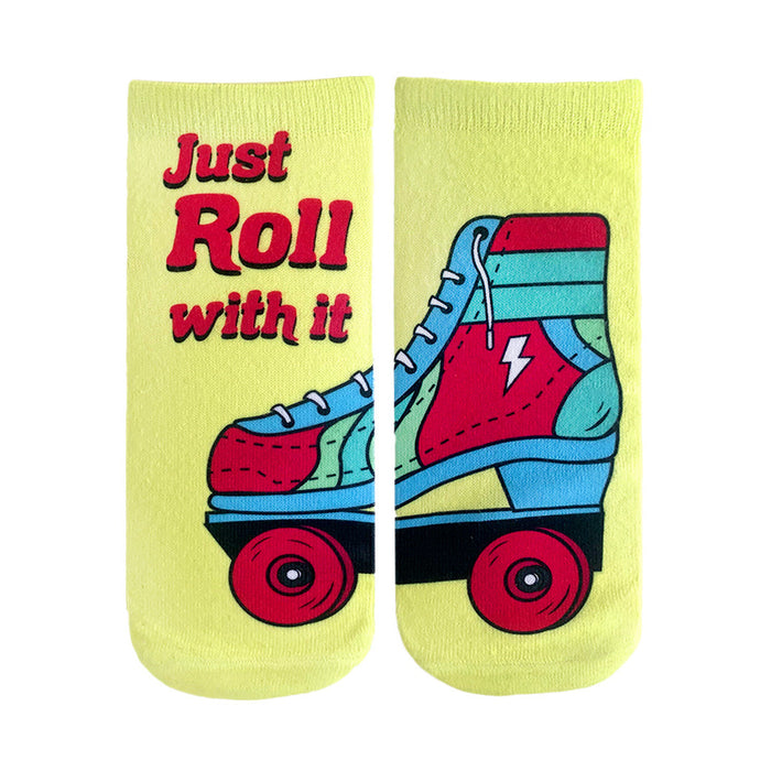 Pair of pastel yellow ankle socks. One sock shows text 'Just Roll With It', the other features a retro-style roller skate graphic with red, blue, and teal accents. }}