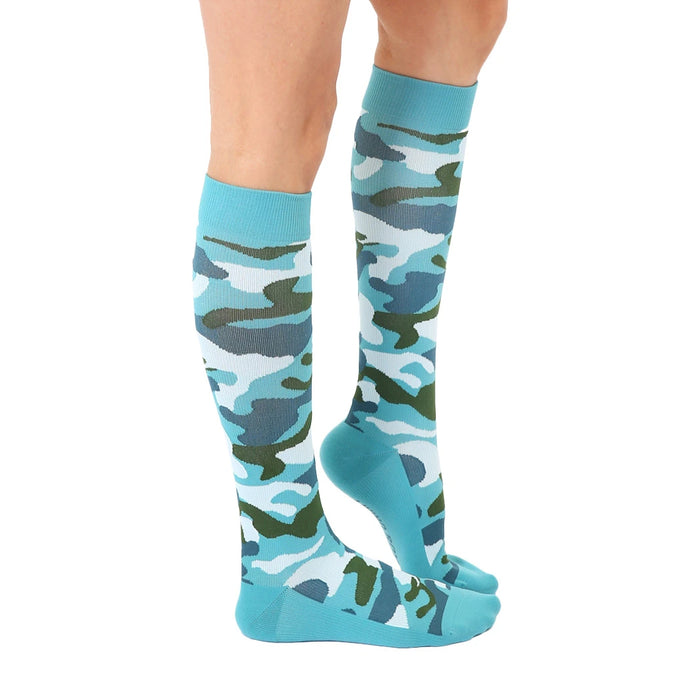 A pair of blue knee-high compression socks with a camouflage pattern in hunter green and navy blue.