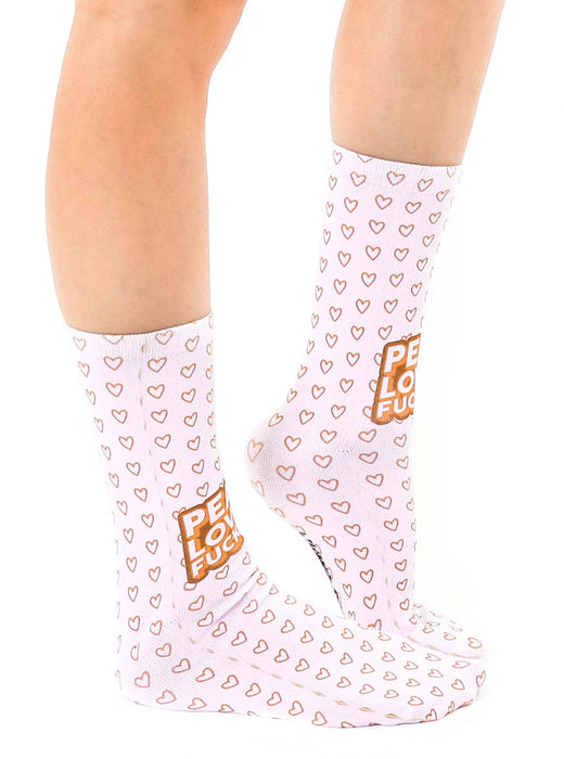 A pair of white socks with a pattern of pink hearts. The word 