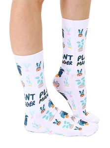 A pair of white socks with a pattern of green and pink plants and the words 