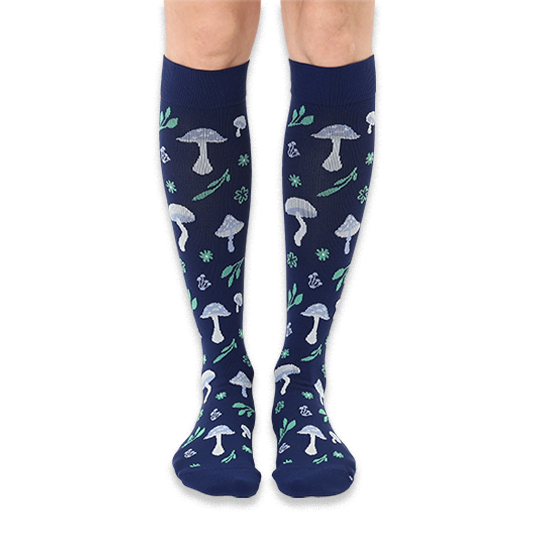 Front view of knee-high dark navy socks featuring a continuous pattern of light blue mushrooms and mint green woodland leaves.