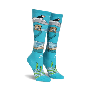 Pair of teal knee-high socks featuring otters, puffins, and icebergs.  Space dye yarn creates a whimsical, underwater scene.