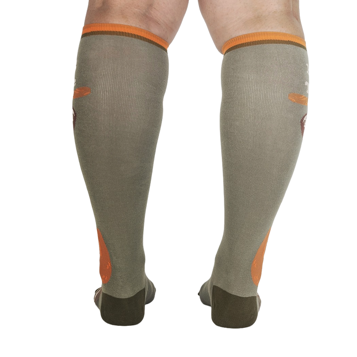 A pair of olive green compression socks with orange accents displayed on the back of a person's legs.