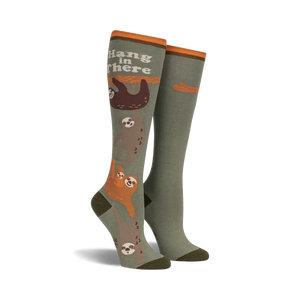Knee-high socks in olive green and orange, featuring a design of sloths hanging from a branch with the text 'Hang in There'.