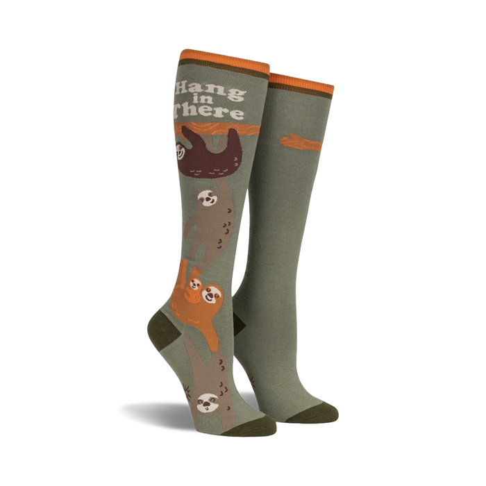 Knee-high socks in olive green and orange, featuring a design of sloths hanging from a branch with the text 'Hang in There'.